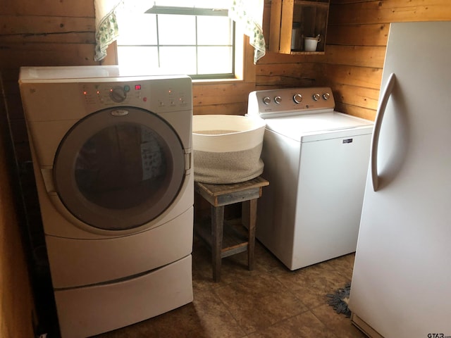 laundry room featuring washer and clothes dryer, wood walls, and tile patterned floors