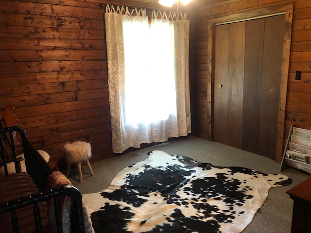 carpeted bedroom with wooden walls and a closet