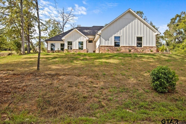 modern farmhouse featuring brick siding, board and batten siding, and a front lawn