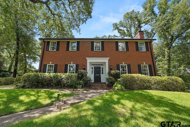 1701 Devonshire Dr, Tyler, TX 75703 - colonial inspired home with a front yard, a chimney, and brick siding