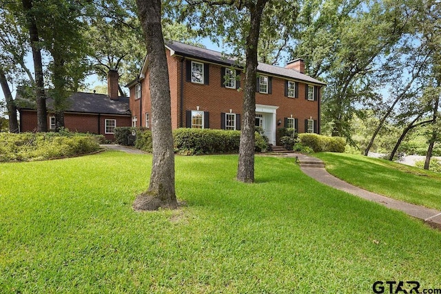 1701 Devonshire Dr, Tyler, TX 75703 - colonial-style house featuring a chimney, a front yard, and brick siding