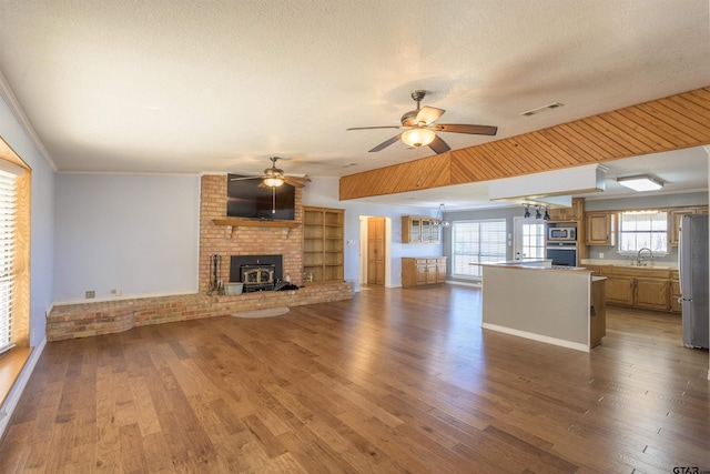 unfurnished living room featuring a sink, ceiling fan with notable chandelier, and wood finished floors