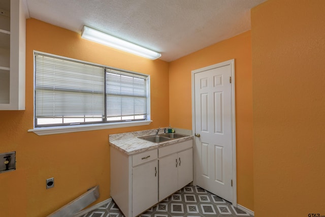 laundry area with a sink, washer hookup, a textured ceiling, hookup for an electric dryer, and cabinet space