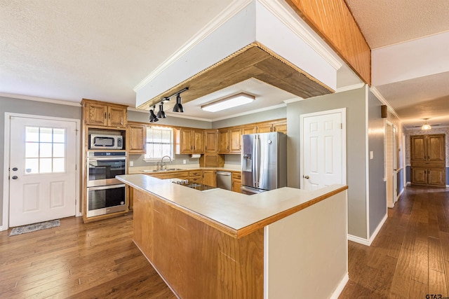 kitchen featuring dark wood-style flooring, ornamental molding, stainless steel appliances, and light countertops