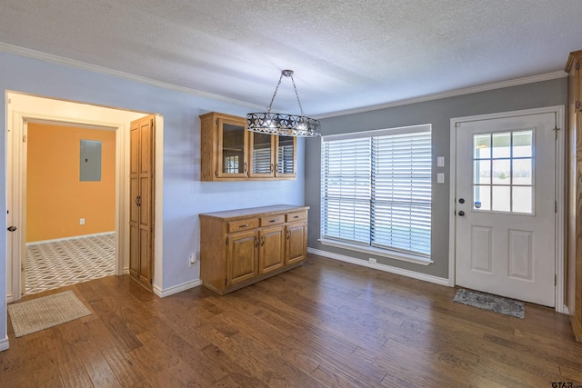 unfurnished dining area with dark wood-type flooring, ornamental molding, a chandelier, and electric panel