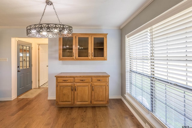 unfurnished dining area with baseboards, ornamental molding, and wood finished floors