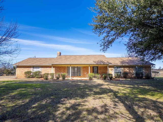 single story home featuring a chimney, a front yard, and brick siding