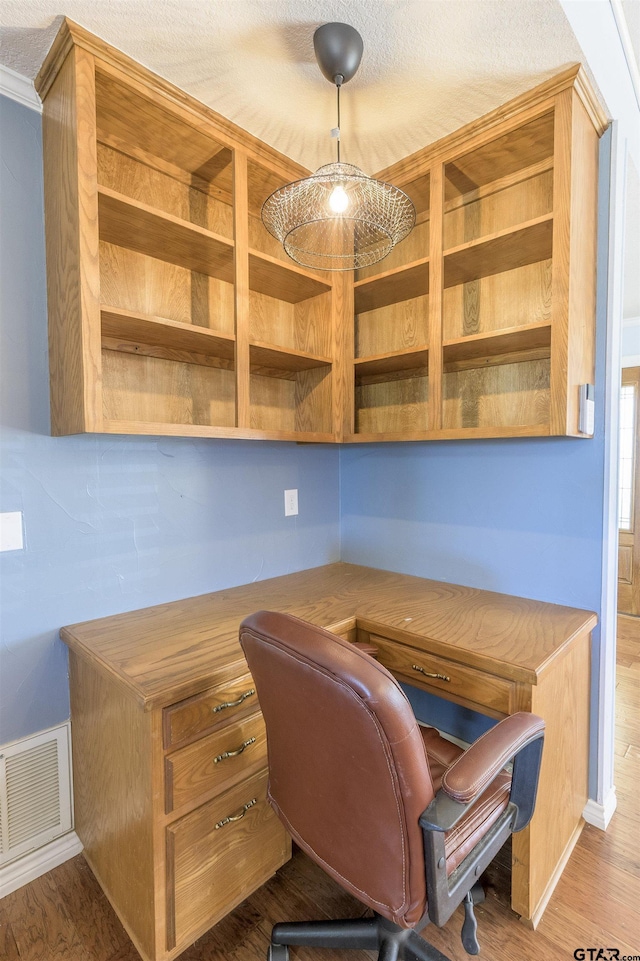 office with built in study area, wood finished floors, and visible vents