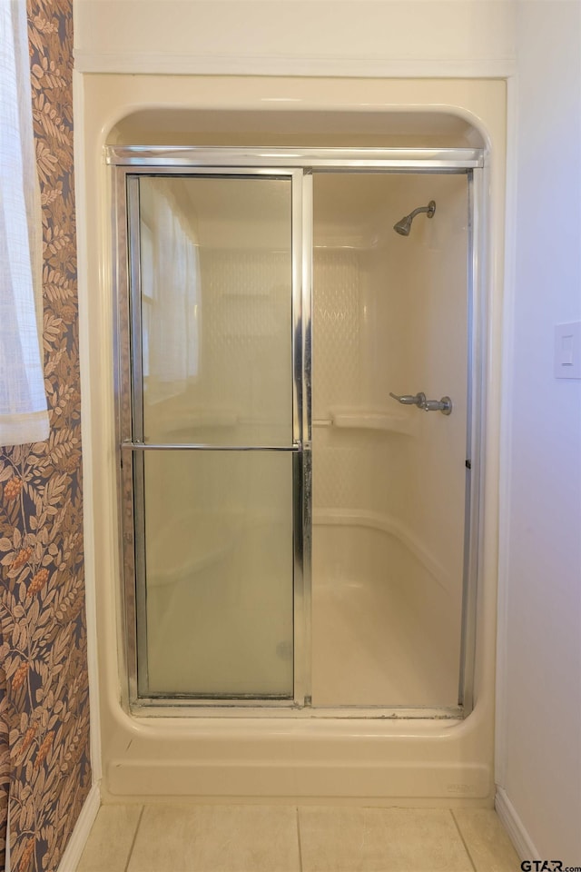 bathroom with a stall shower, tile patterned floors, and wallpapered walls