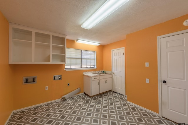 laundry area featuring hookup for an electric dryer, hookup for a washing machine, a textured ceiling, a sink, and cabinet space