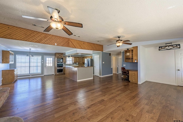 unfurnished living room with dark wood-style flooring, a textured ceiling, visible vents, baseboards, and a ceiling fan