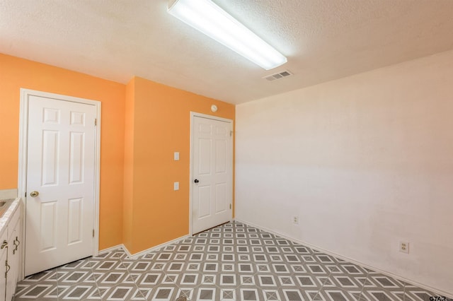 spare room featuring a textured ceiling, visible vents, and tile patterned floors