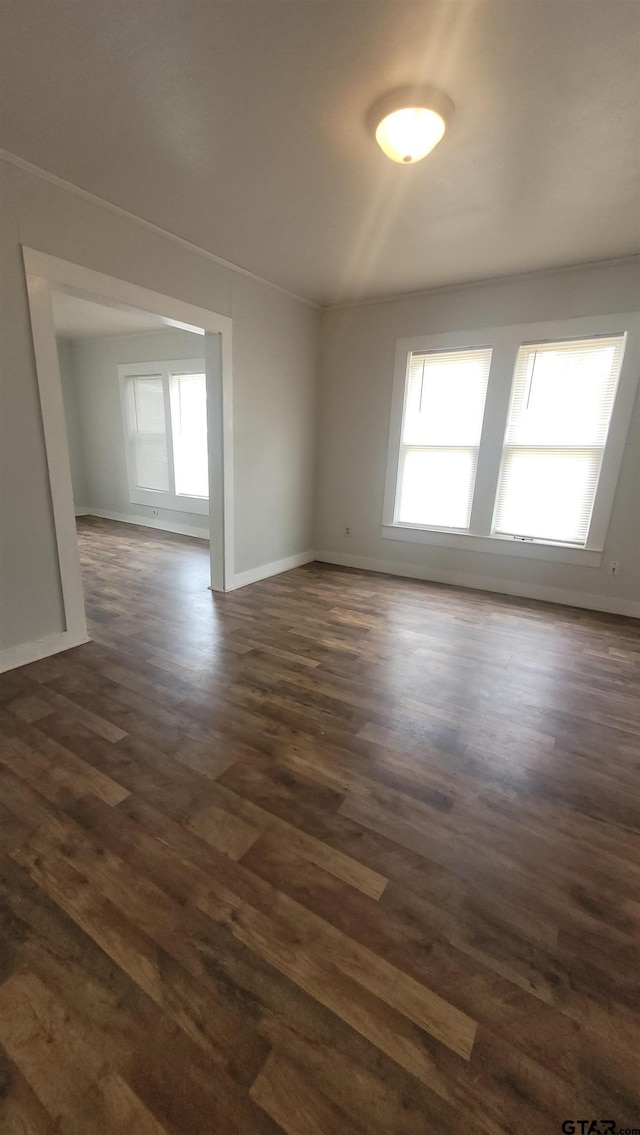 empty room featuring baseboards and dark wood-style floors