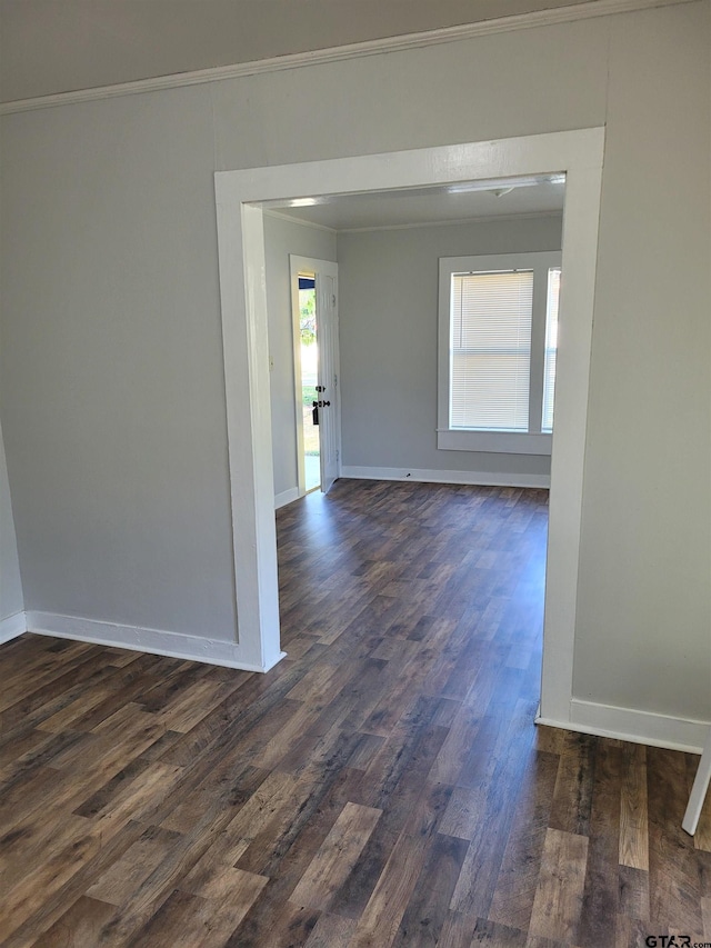 unfurnished room with dark wood-style flooring, baseboards, and ornamental molding