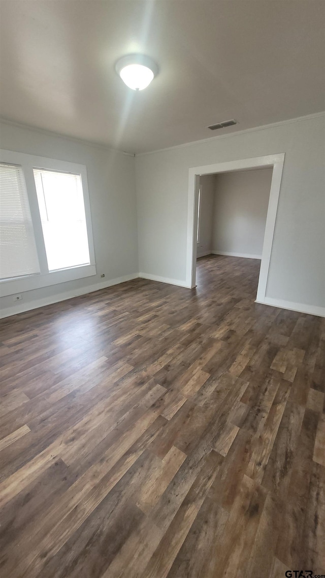 empty room featuring baseboards, dark wood-style floors, and visible vents