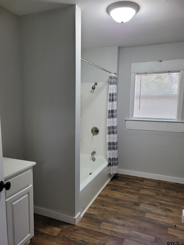 bathroom with vanity, baseboards, wood finished floors, and shower / tub combo