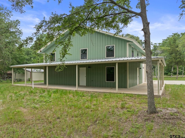 back of property with a lawn, a patio, and a carport