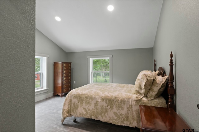 bedroom featuring lofted ceiling, multiple windows, and light hardwood / wood-style flooring