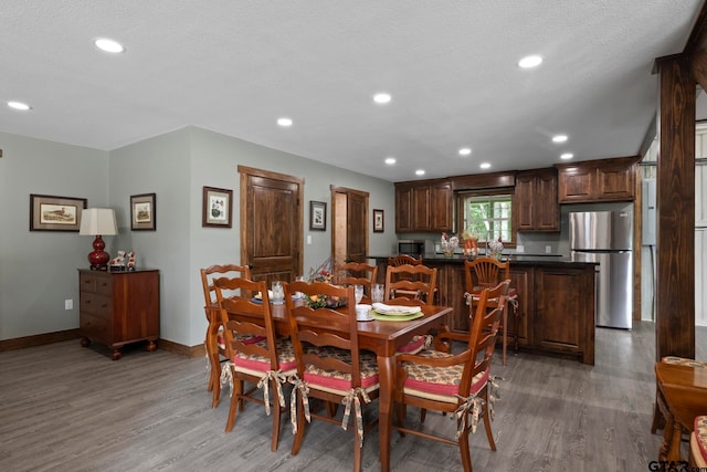 dining space with wood-type flooring and a textured ceiling