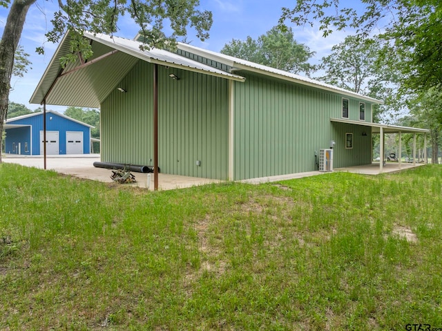 view of property exterior with a garage, an outdoor structure, central AC, and a yard