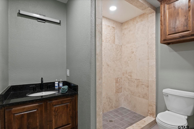 bathroom featuring tiled shower, toilet, and vanity