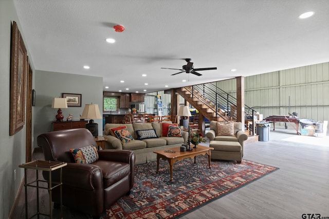 living room with wood-type flooring, ceiling fan, and a textured ceiling