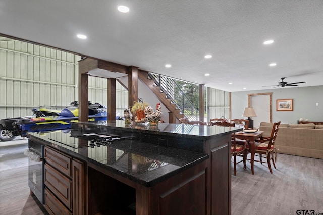 kitchen with dark stone countertops, light wood-type flooring, a textured ceiling, and ceiling fan