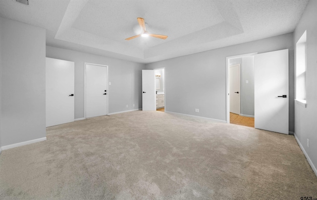 4715 Edinburgh Dr, Tyler, TX 75703 - unfurnished bedroom featuring carpet floors, a tray ceiling, ensuite bath, baseboards, and a ceiling fan