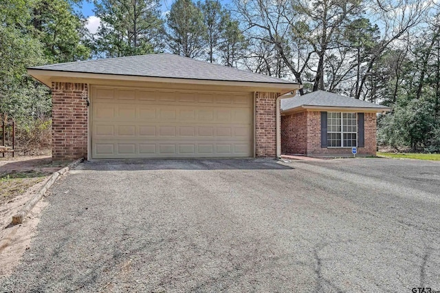 ranch-style house with brick siding, a shingled roof, and aphalt driveway