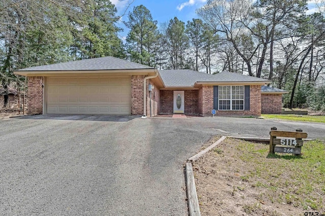single story home featuring aphalt driveway, a garage, brick siding, and a shingled roof