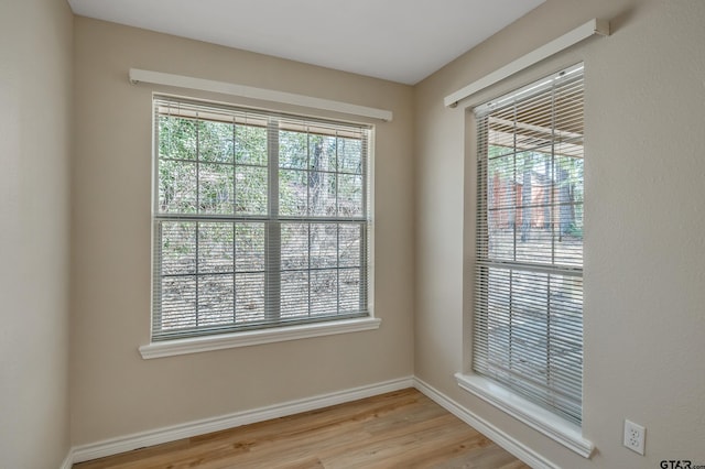 unfurnished room featuring plenty of natural light, baseboards, and light wood-type flooring