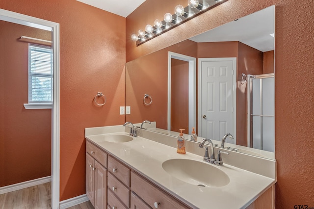 full bathroom featuring an enclosed shower, wood finished floors, baseboards, and a sink