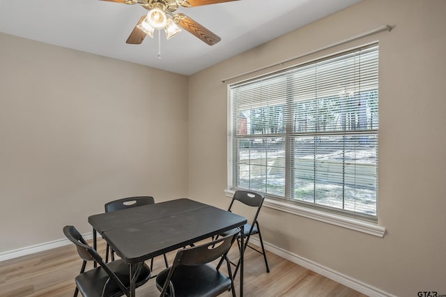 dining space featuring baseboards, a ceiling fan, and light wood finished floors