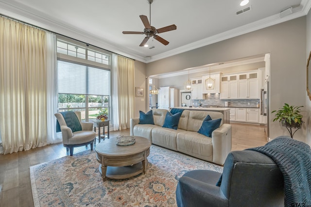 living room with crown molding, ceiling fan, and light wood-type flooring