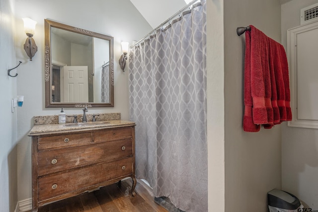 bathroom with vanity, wood-type flooring, vaulted ceiling, and walk in shower