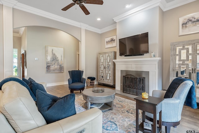 living room featuring light hardwood / wood-style flooring, ceiling fan, and ornamental molding