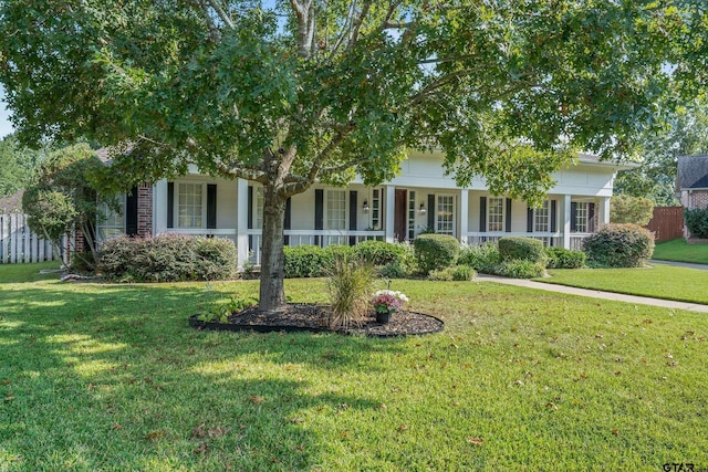 view of property hidden behind natural elements with a porch and a front lawn