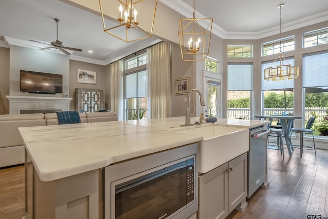 kitchen with pendant lighting, a center island with sink, ceiling fan, appliances with stainless steel finishes, and dark hardwood / wood-style flooring