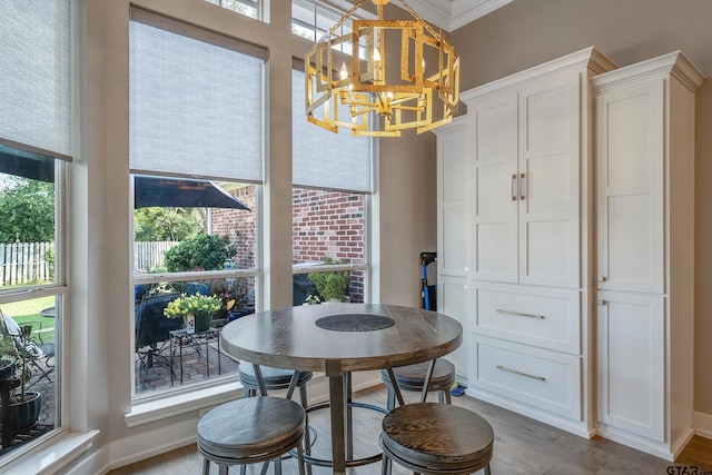 dining area with wood-type flooring, a notable chandelier, and ornamental molding