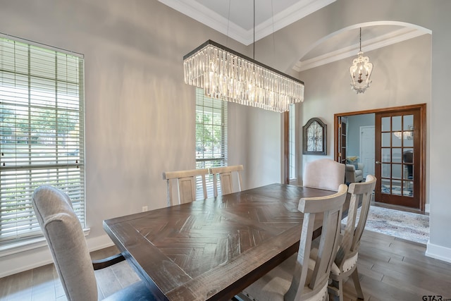 dining area featuring a healthy amount of sunlight, ornamental molding, dark wood-type flooring, and an inviting chandelier