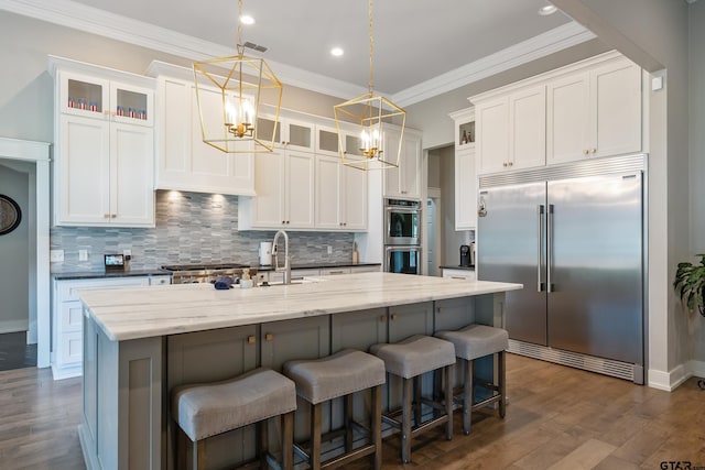 kitchen featuring white cabinetry, dark wood-type flooring, stainless steel appliances, and an island with sink