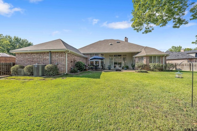 back of property with a lawn, central air condition unit, and a patio