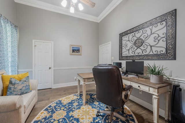 office featuring wood-type flooring, a towering ceiling, ceiling fan, and crown molding