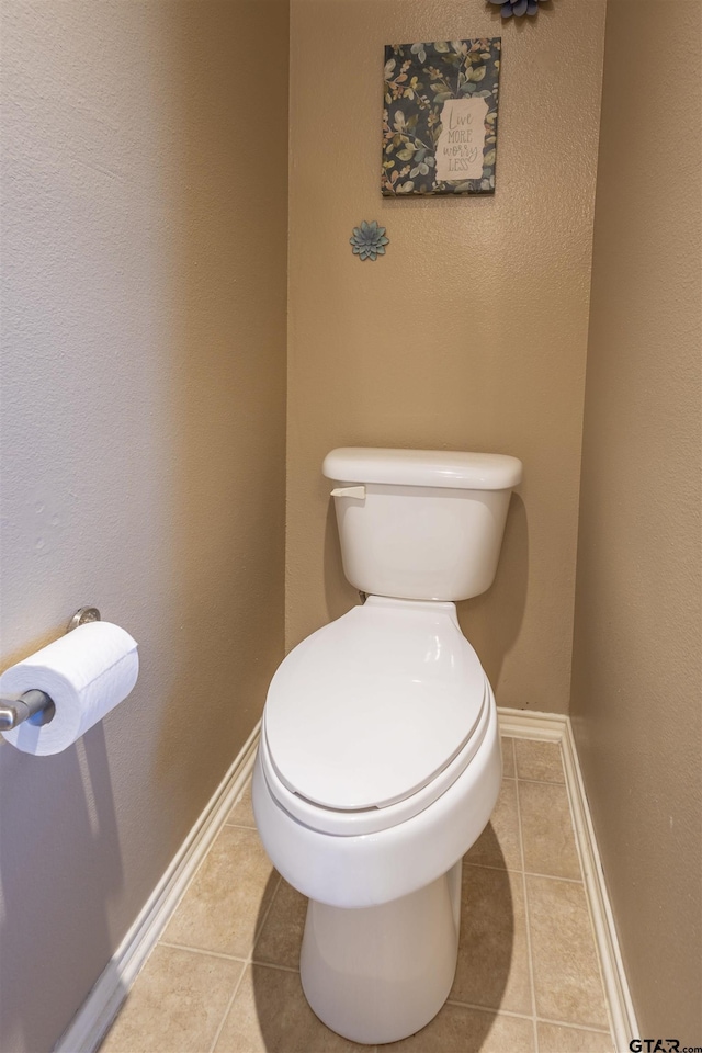 bathroom featuring toilet, baseboards, and tile patterned flooring