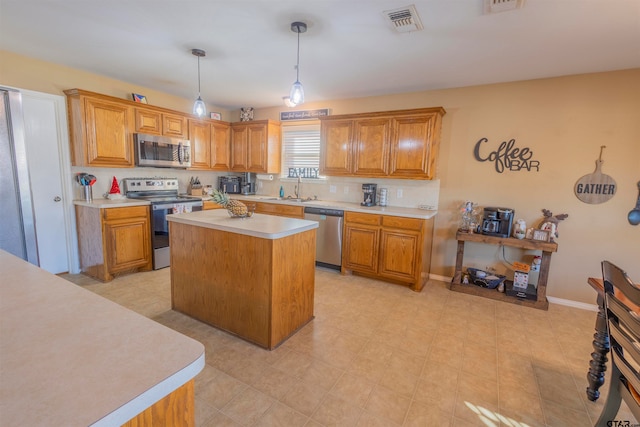 kitchen with appliances with stainless steel finishes, a center island, hanging light fixtures, and sink