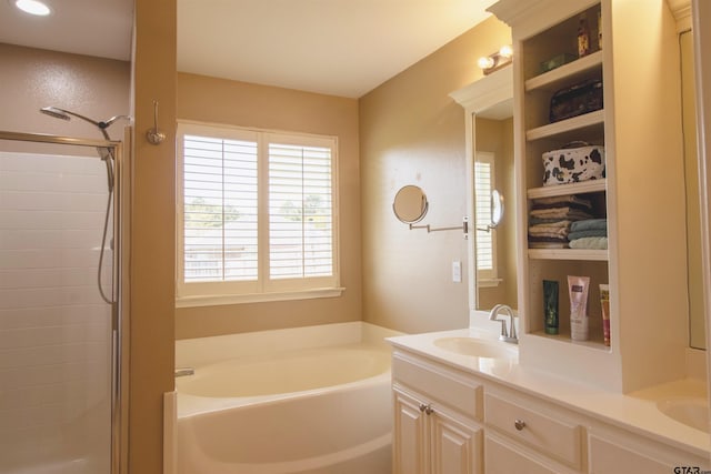 bathroom with a garden tub, double vanity, a sink, and plenty of natural light