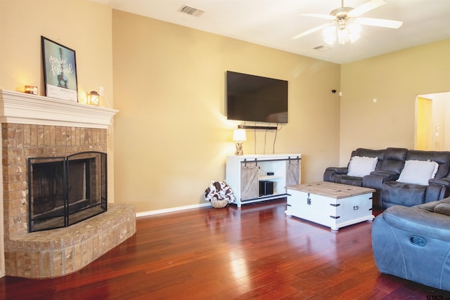 living room with ceiling fan, visible vents, wood-type flooring, a brick fireplace, and baseboards