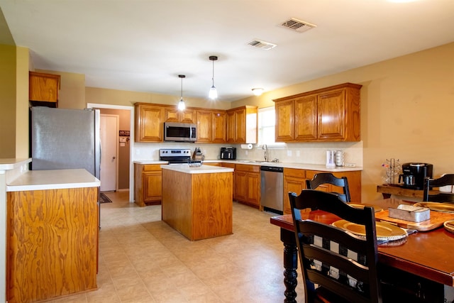 kitchen featuring visible vents, brown cabinetry, appliances with stainless steel finishes, and a kitchen island
