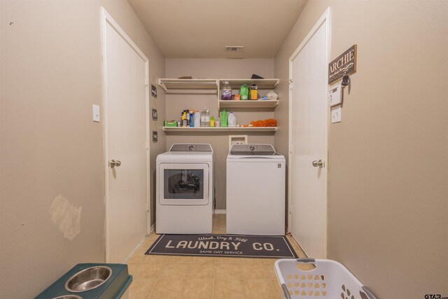 washroom featuring visible vents, washer and clothes dryer, tile patterned flooring, and laundry area