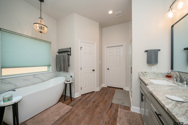 4523 Lone Oak Ln, Longview, TX 75605 - full bath with wood finished floors, a freestanding bath, double vanity, a chandelier, and recessed lighting